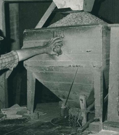 A vintage photograph of a mill grain hopper marked No 3 with an arm reaching toward it